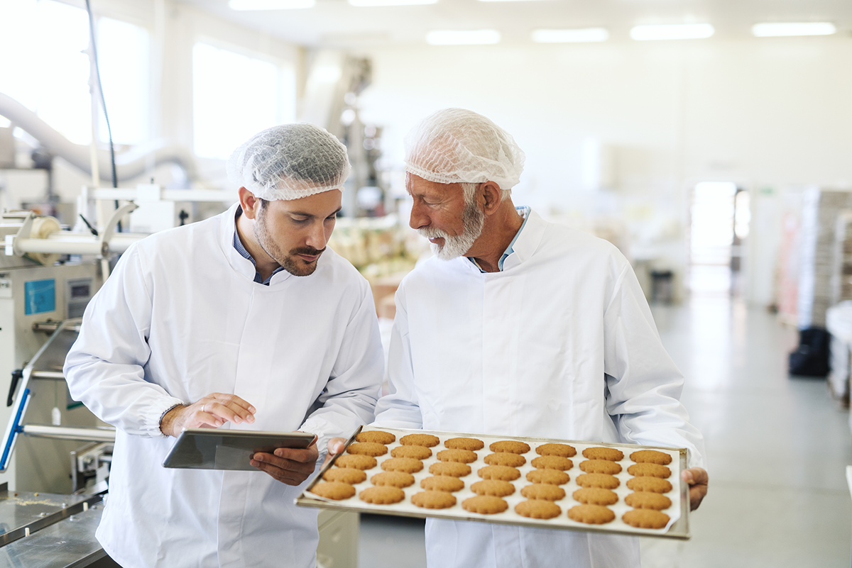 Zdjęcie dwóch techników przeprowadzających testy w celu zastąpienia składników, takich jak jajka, lub zmniejszenia ilości cukru, tłuszczu lub glutenu w celu obniżenia kosztów materiałowych.